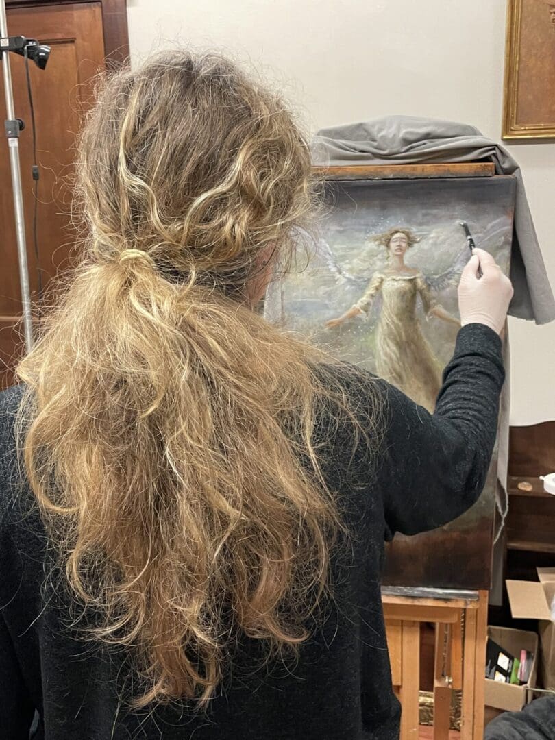 Artist restoring a painting on an easel.