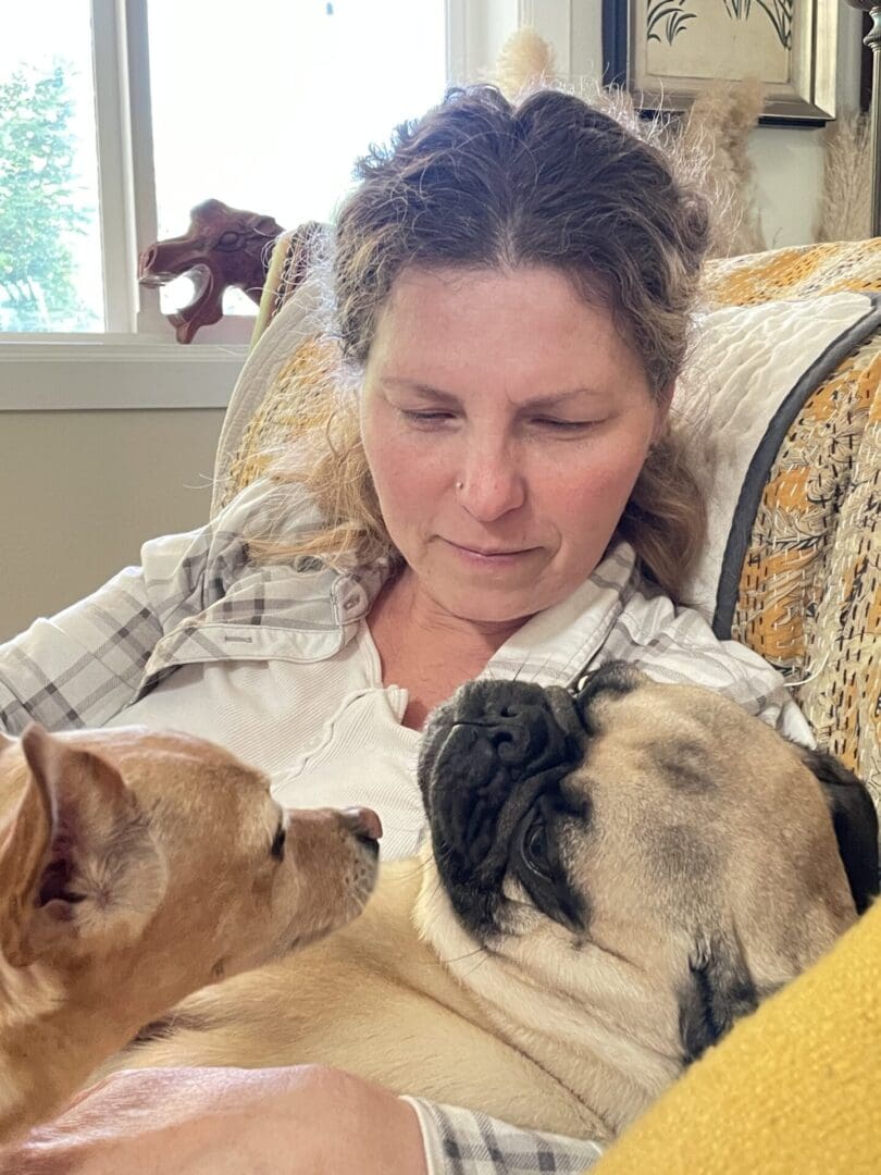 Woman cuddling with two small dogs.